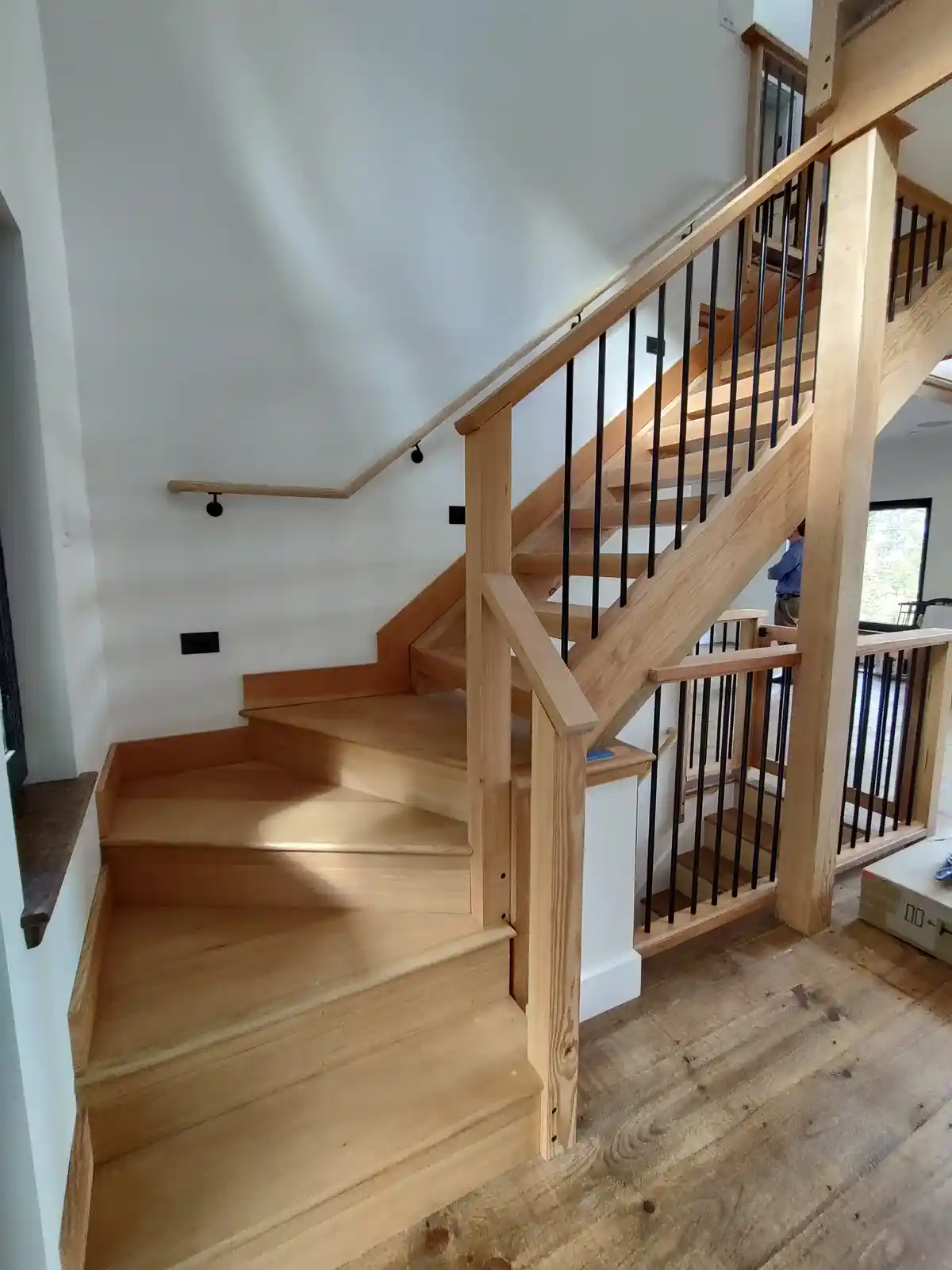 A newly built wooden staircase with black metal railings is shown inside a house, but it appears to terminate abruptly at a…