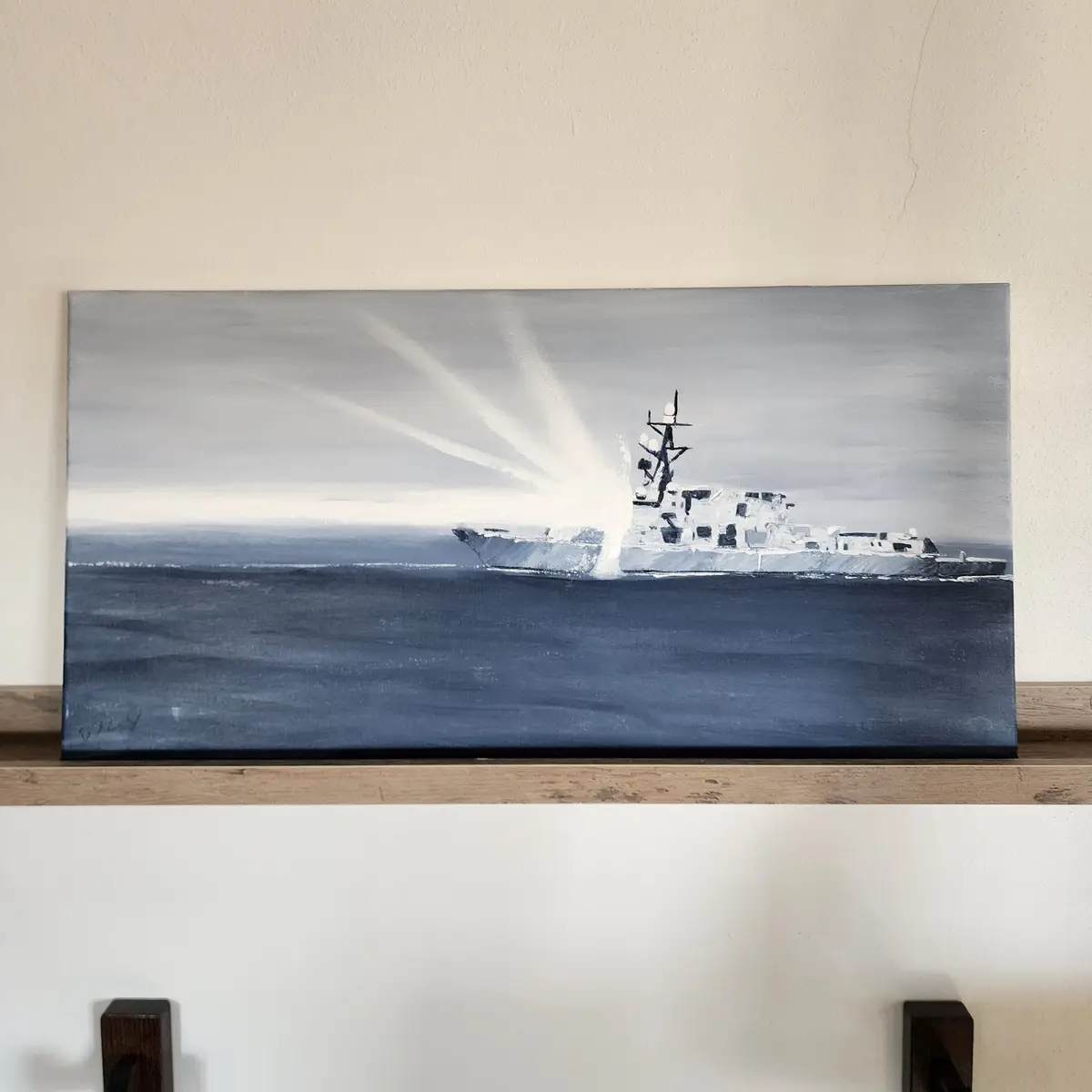 A black-and-white painting of a warship on the ocean, with bright white rays emanating from its bow, hangs on a wall. The…
