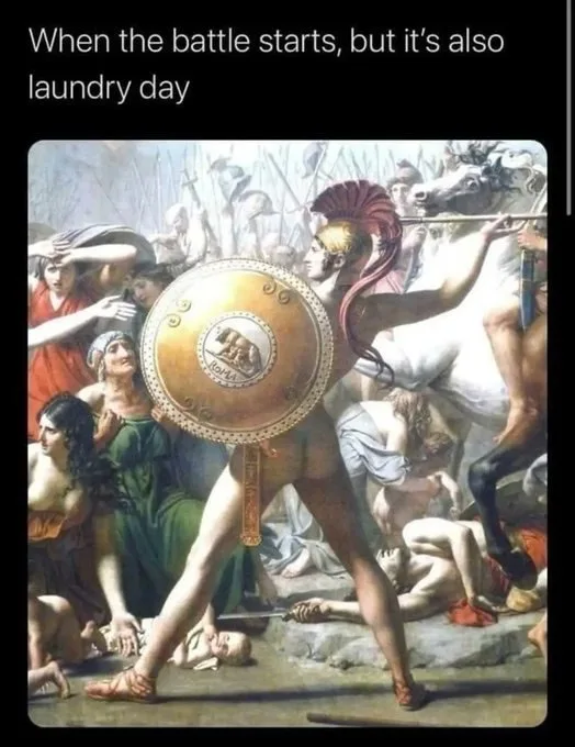 A classical painting depicts a Spartan warrior in battle gear holding a large round shield, surrounded by chaotic scenes of…