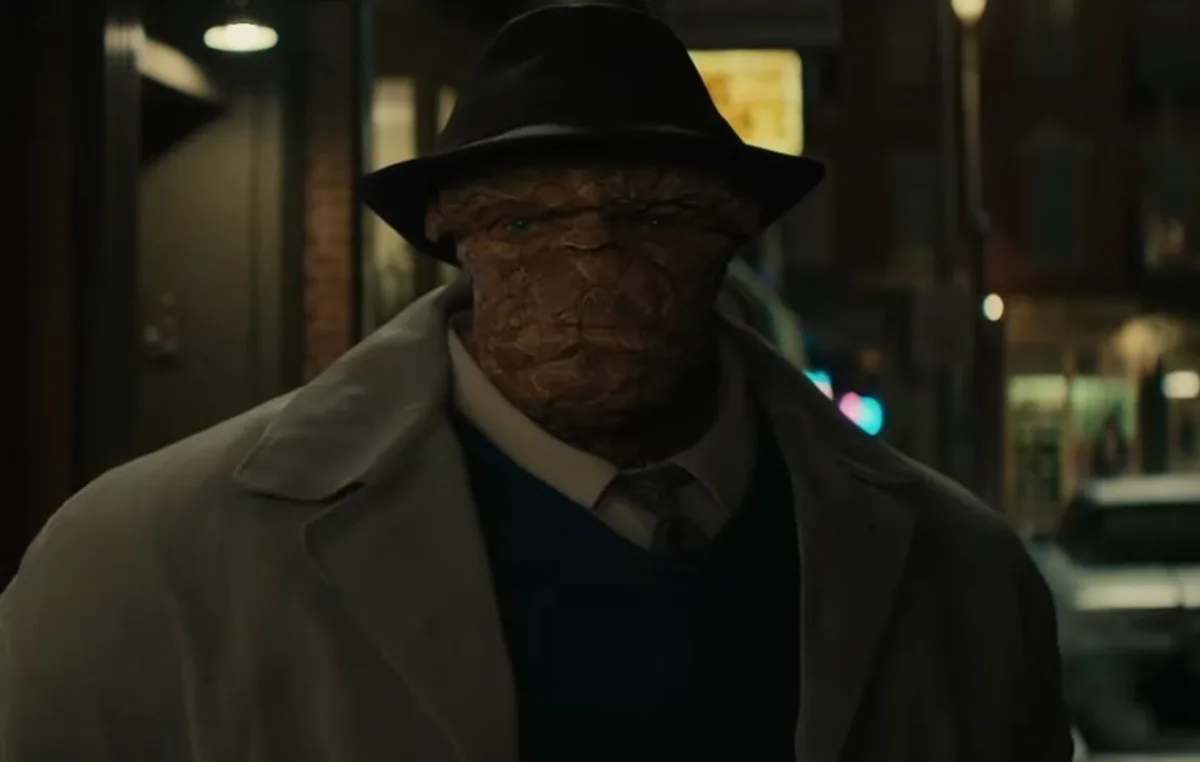 A close-up of a character with a textured, brown, reptilian-like face wearing a black fedora, a beige trench coat, a white…