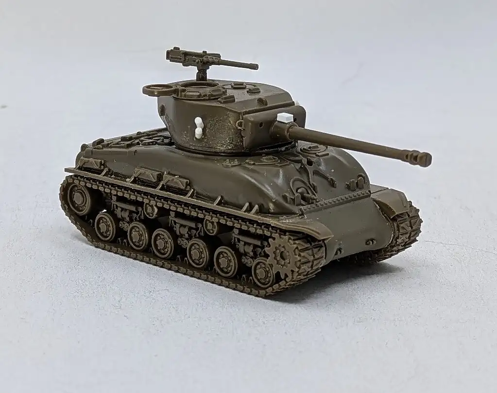 A detailed olive-drab model of a World War II-era American medium tank, likely a Sherman, is photographed against a plain…