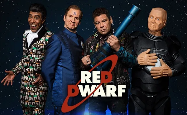 Four men in sci-fi costumes stand against a starry space background, with the 'Red Dwarf' logo prominently displayed in red…