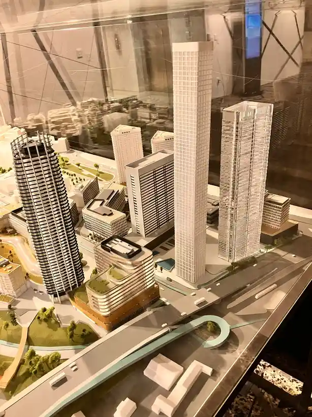 A detailed architectural model of a modern cityscape with numerous skyscrapers, roads, and green spaces, displayed under…