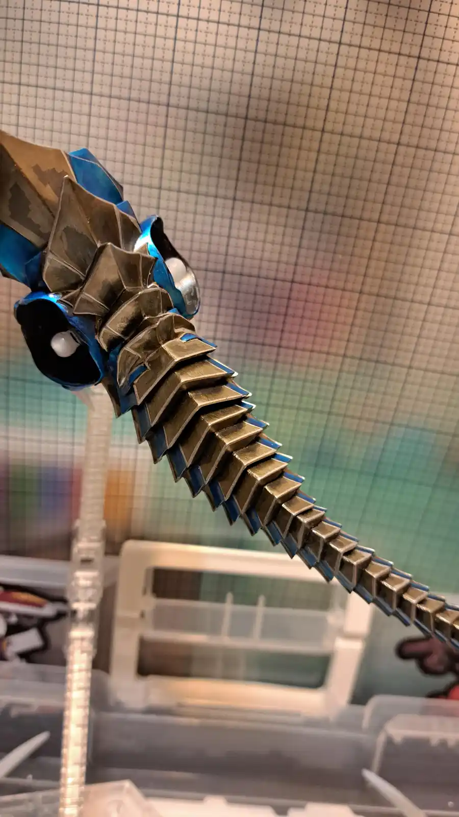 A close-up photo shows a handmade sword crafted from folded paper, featuring a metallic gold blade with blue accents and a…