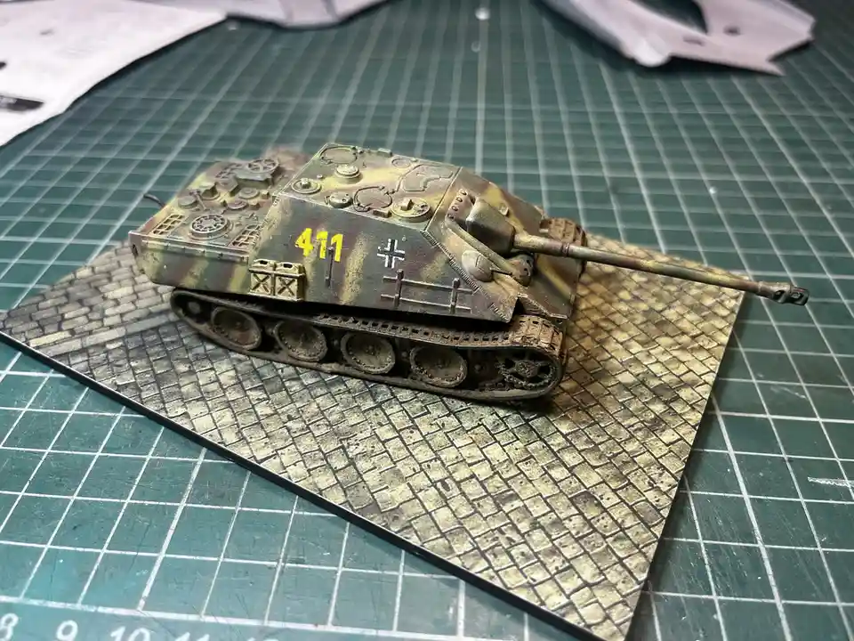 A detailed scale model of a German tank, painted with camouflage and marked with the number 411 and a cross symbol, sits on…