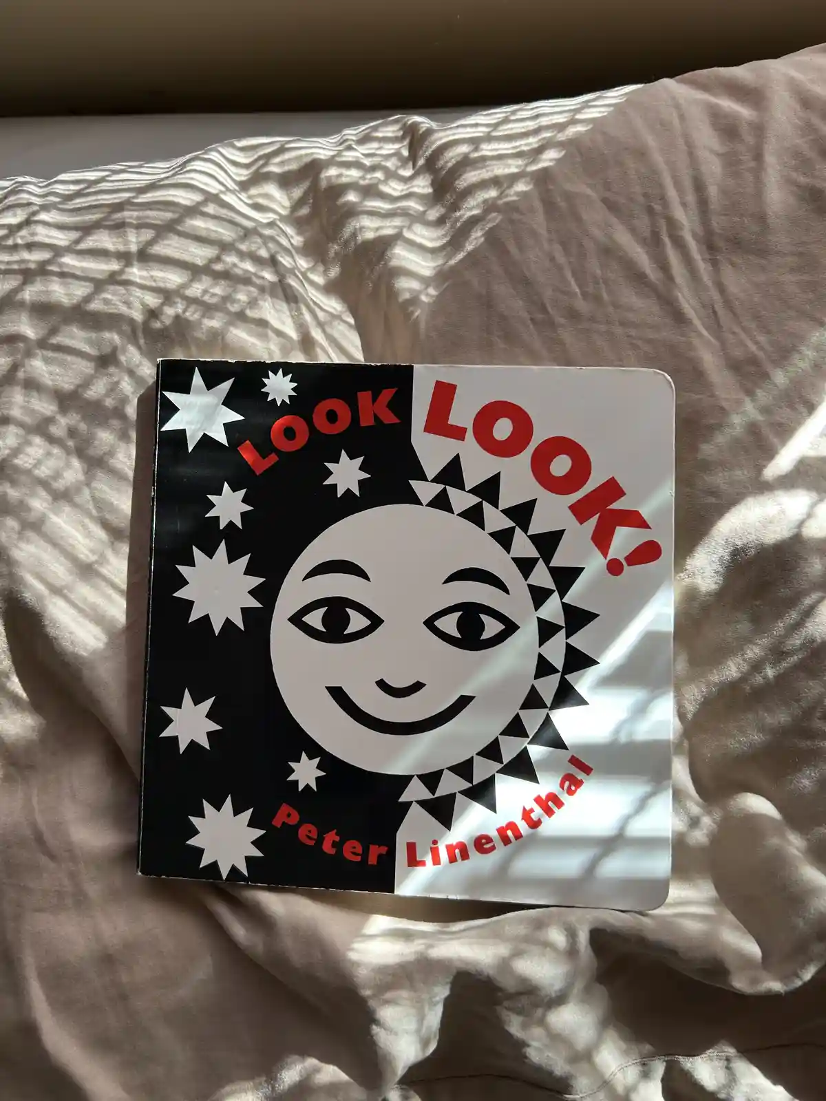 A children's book titled 'Look Look!' by Peter Linenthal, featuring a smiling sun with a black-and-white geometric design…