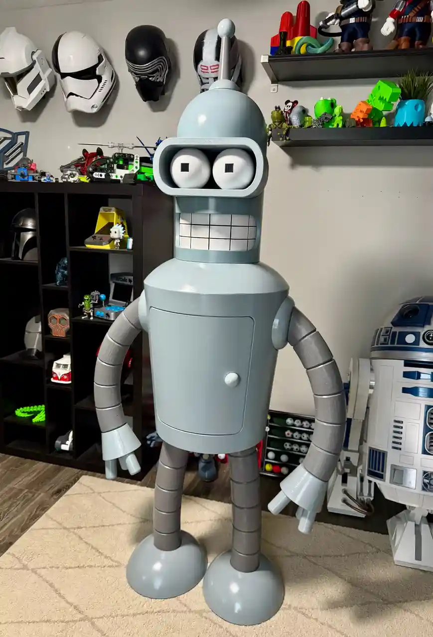 A large, light-gray robot with big square eyes and a gridded mouth stands in a room filled with pop culture collectibles…