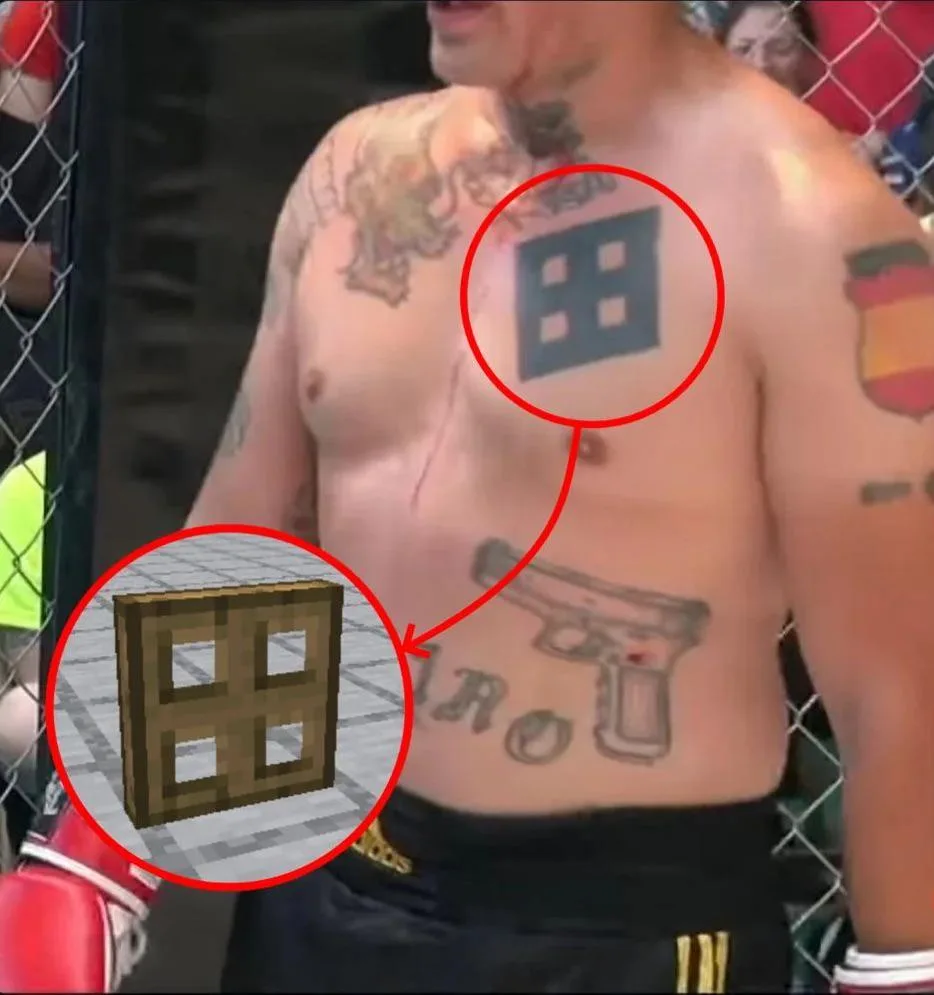 A shirtless man with tattoos stands in a cage, his chest tattoo of a blue square with four smaller squares inside is circled…