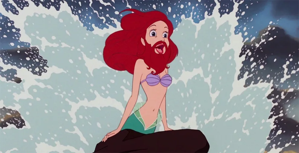 A red-haired mermaid with a purple top and green tail sits on a rock amidst crashing ocean waves, but her face has been…