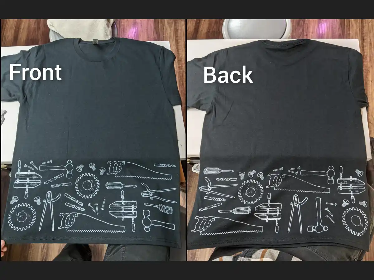 A split image shows the front and back of a black t-shirt, both featuring identical white line drawings of various tools…