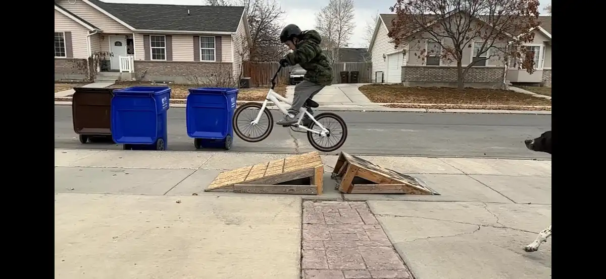 Watch the boy conquer the jump his dad built, learning to pull up like a pro!
