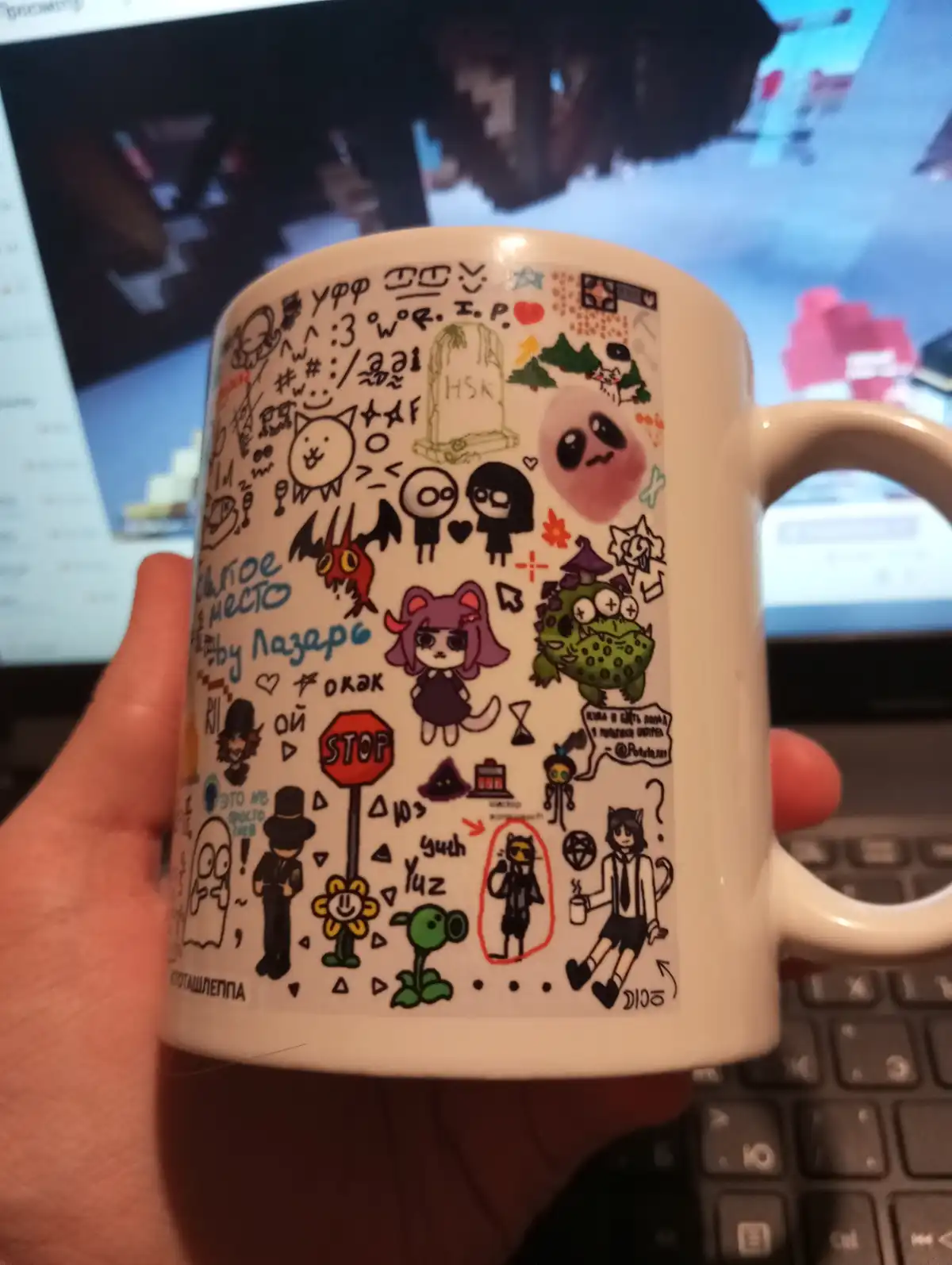 A hand holds a white mug covered in colorful, hand-drawn doodles of anime-style characters, symbols, and text in Russian and…