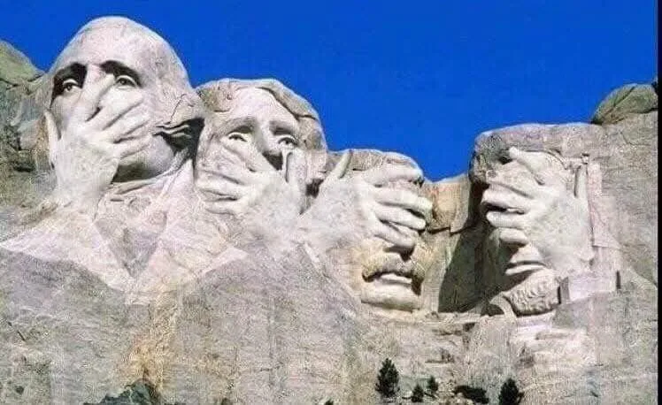 The image shows the Mount Rushmore National Memorial with the carved faces of four U.S. presidents. Each president's hand is…