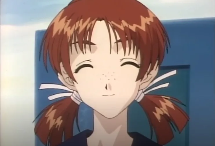 An anime girl with brown pigtails and a blue collar smiles blissfully with her eyes closed, her expression conveying pure…