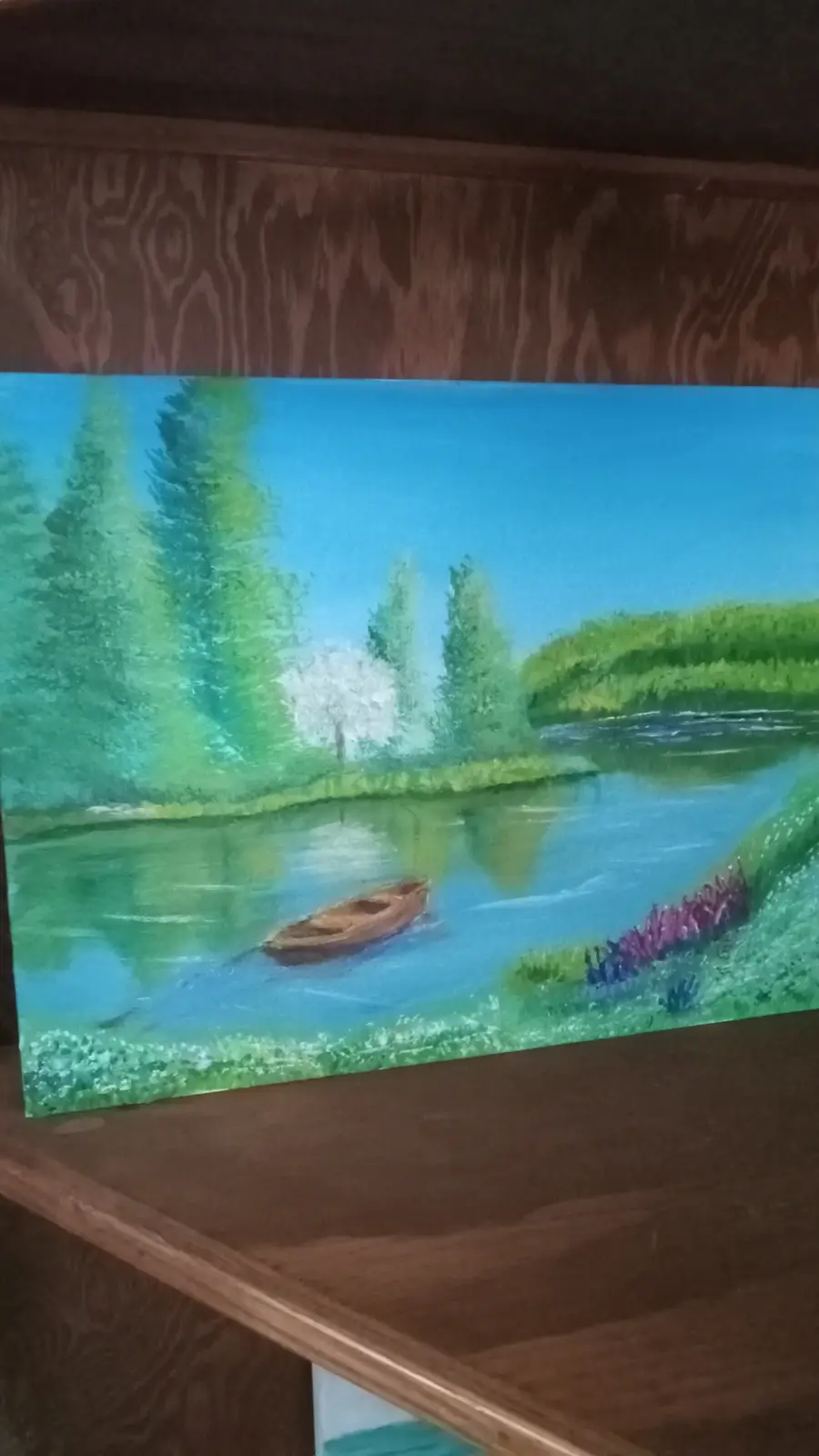 A painting of a serene river scene with green trees, a white flowering tree, and a small boat floating on calm water…