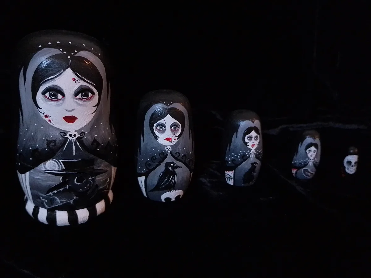 A set of five hand-painted Russian nesting dolls arranged in decreasing size from left to right against a black background…
