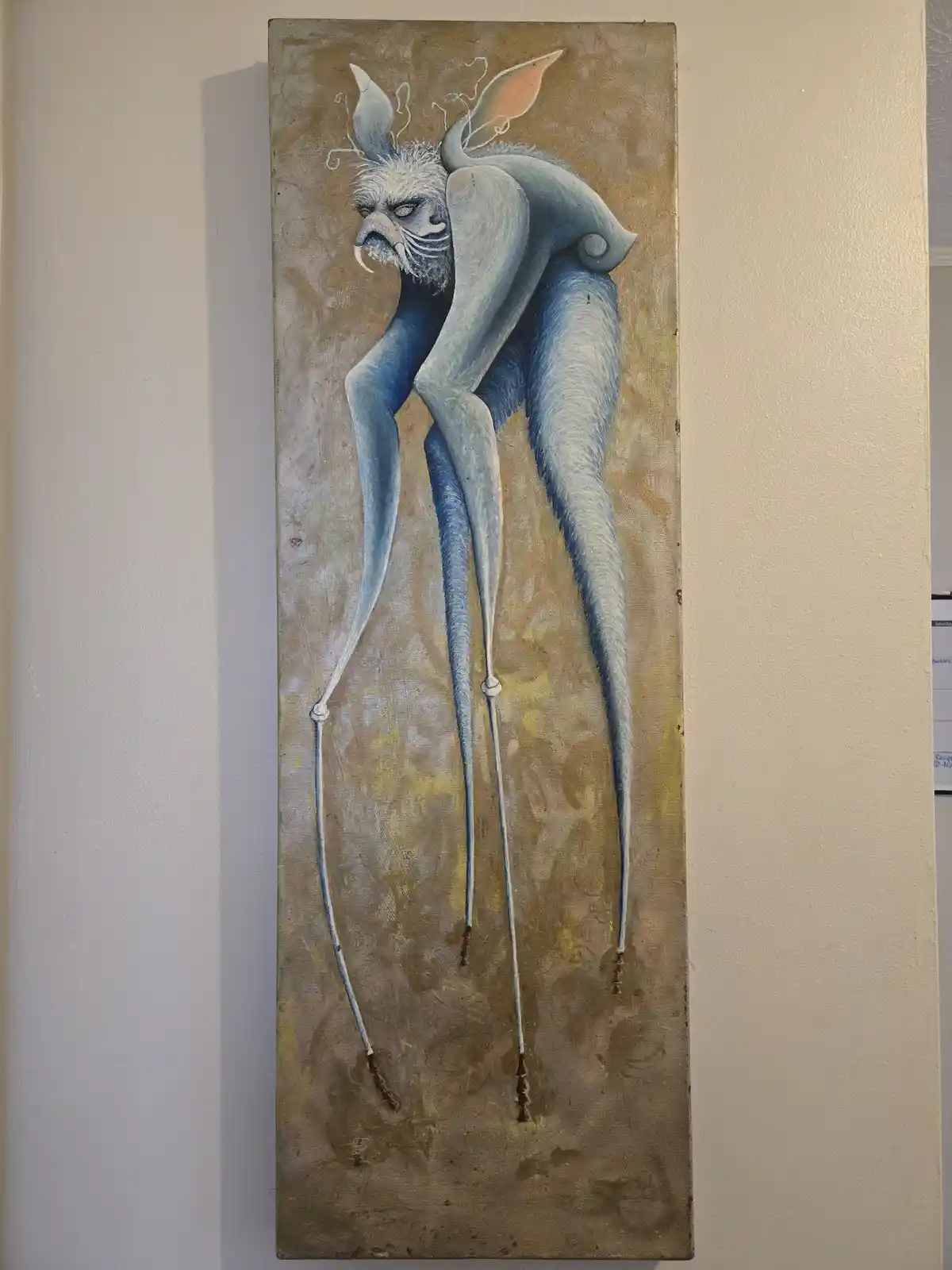 A tall, narrow painting depicts a blue, furry, humanoid creature with long, thin legs ending in pointed feet, large ears…