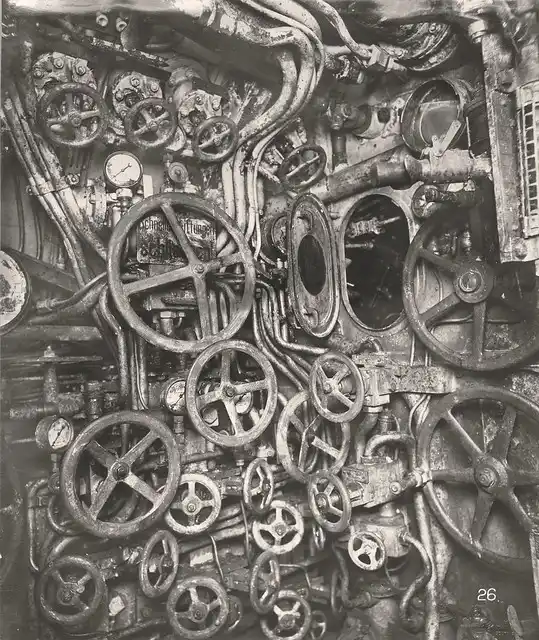 A black-and-white photo shows a dense, cluttered wall of old, rusty industrial valves, pipes, and gauges. Overlaid text…