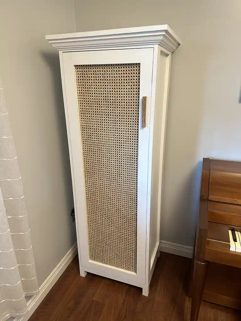 A tall, white cabinet with a woven cane door stands in a room next to a wooden piano, with text overlaid that reads 'i made…