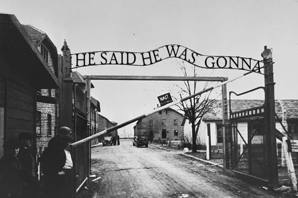 A black-and-white historical photo shows a large gate with a horizontal bar lowered across a road, blocking passage. Several…