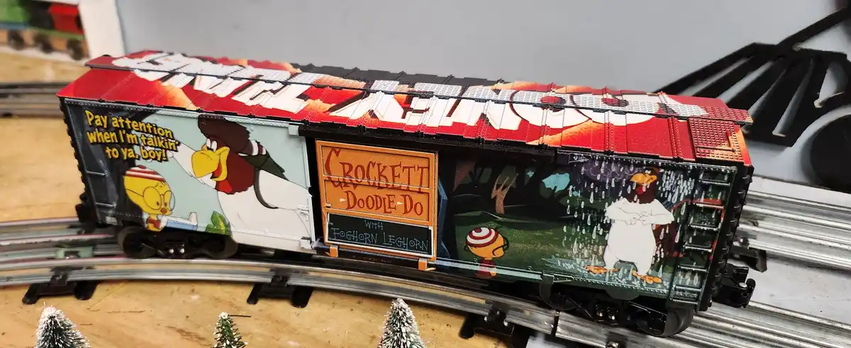 A model train car decorated with scenes from the Looney Tunes show 'Crockett Doodle Do with Foghorn Leghorn', featuring…