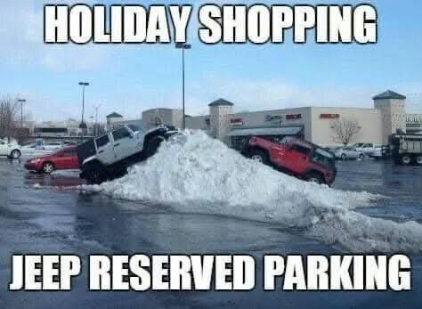 Two jeeps are stuck in a large snowbank in a parking lot, with a shopping mall visible in the background. The top text reads…