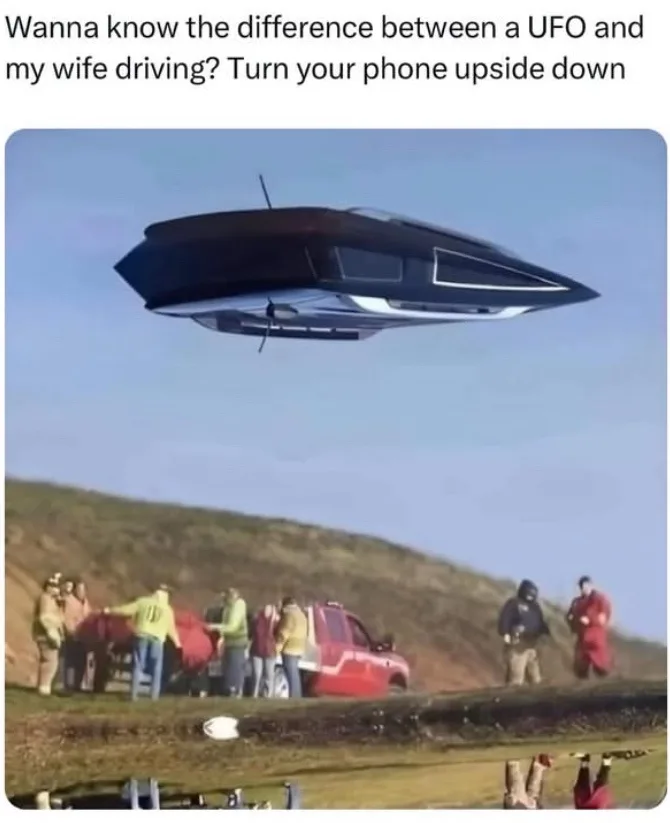 The image shows a black, sleek, disc-shaped UFO hovering in the sky above a grassy hill. Below, a group of people in casual…