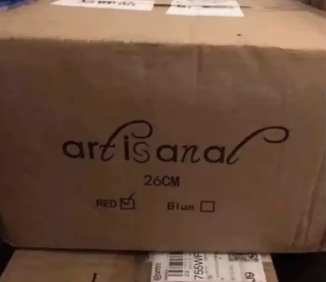 A close-up of a plain brown cardboard box with the word 'artisanal' printed in a cursive font, followed by '26CM' and two…