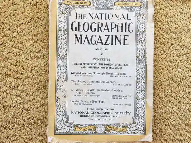 An old, yellowed copy of The National Geographic Magazine from May 1926, Volume XLIX, Number Five, lies on a beige carpet…