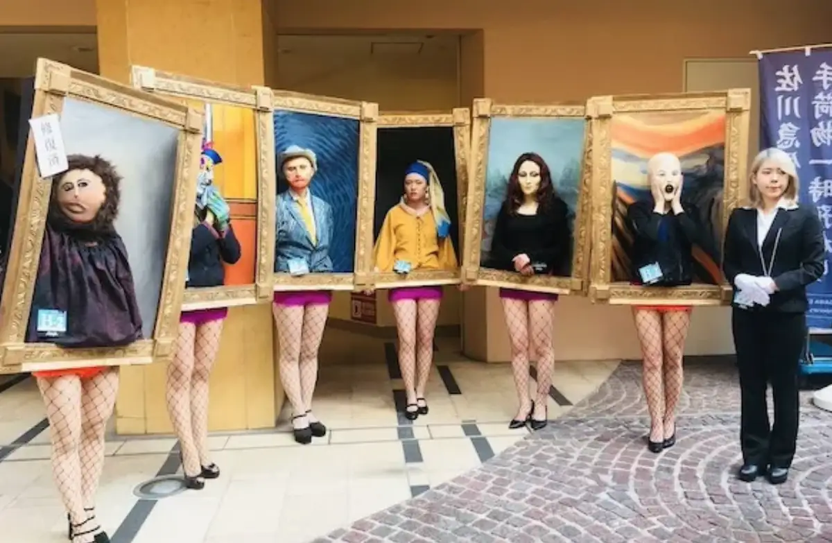 Five women in fishnet stockings and heels hold large, ornate picture frames, each portraying a different famous painting…