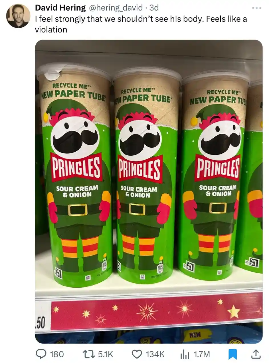 Three Pringles cans with elf-themed holiday packaging are lined up on a store shelf, each featuring a cartoon elf with a…