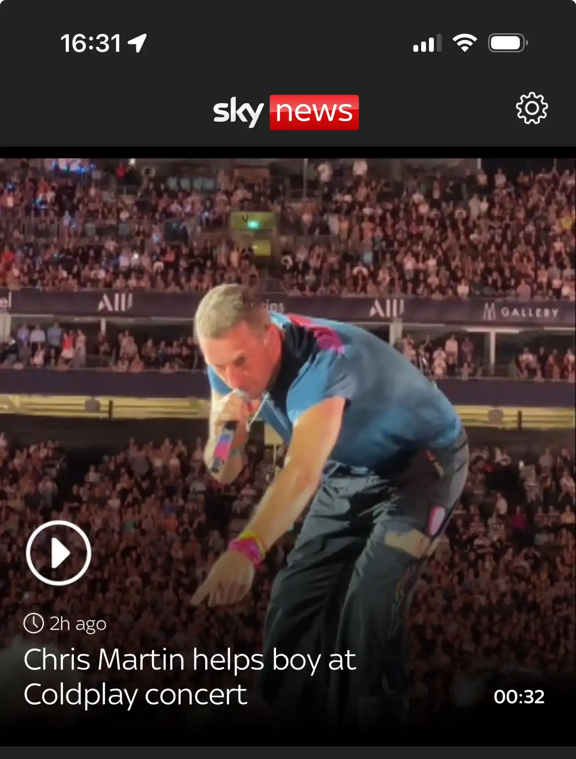 A screenshot of a Sky News video thumbnail shows Coldplay frontman Chris Martin bent over, holding a microphone and pointing…