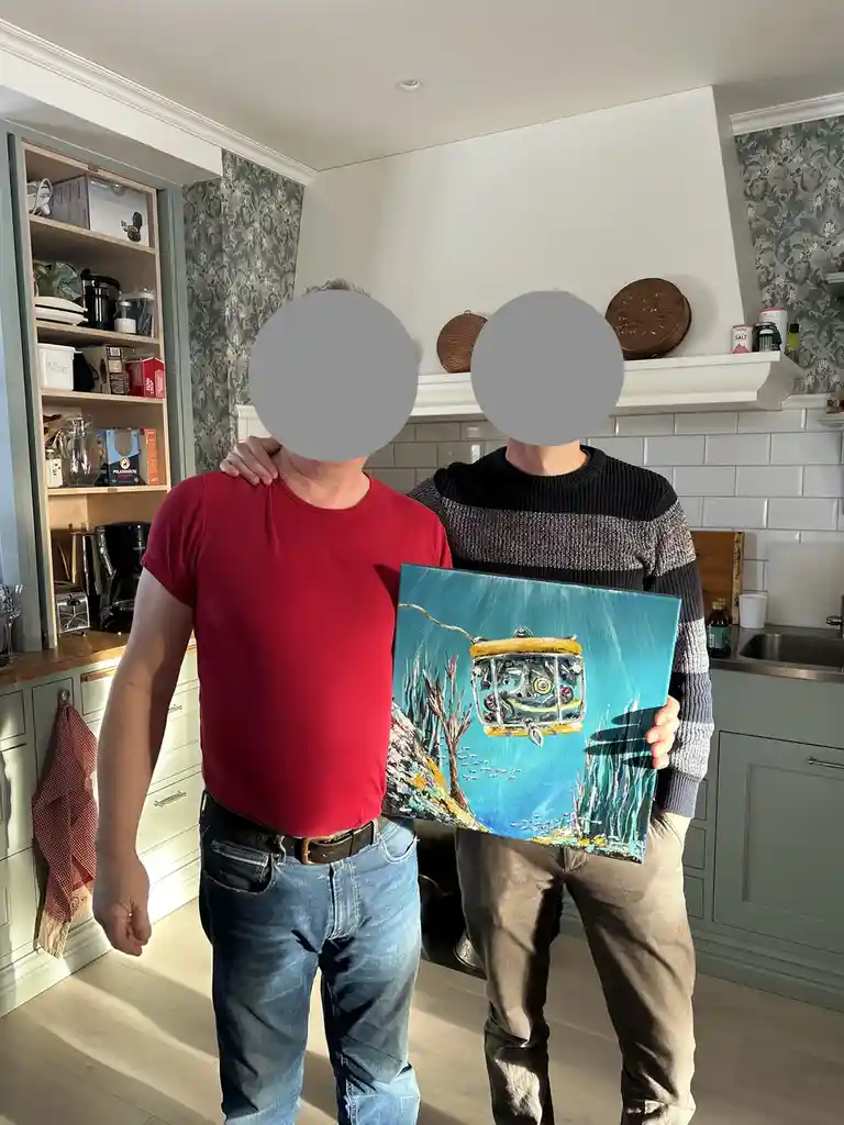 Two men stand in a kitchen, their faces obscured by gray circles, holding a painting that depicts a yellow submarine-like…