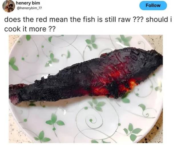 A charred, blackened fish on a white plate with green leaf patterns has a visible red interior, prompting confusion about…