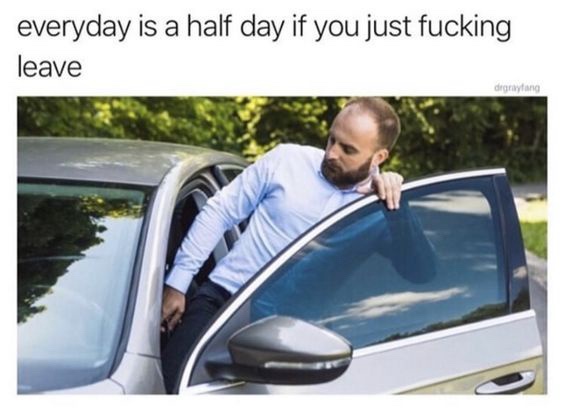 A man with a beard and light blue shirt leans out of the open driver's side door of a silver car, looking down and away with…