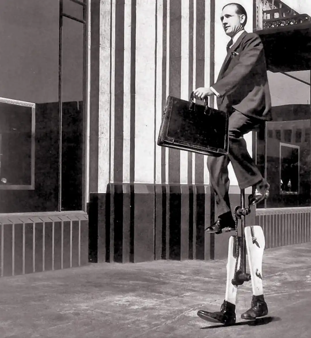 A black-and-white photo shows a man in a suit and tie walking outdoors while carrying a briefcase. His legs are replaced…