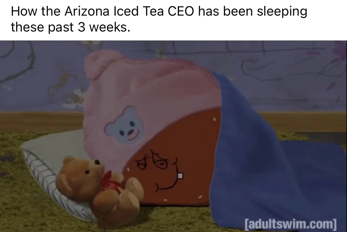 A cartoonish, brown, round character with a drawn-on tired face is tucked under a blue blanket and wearing a pink hat with a…