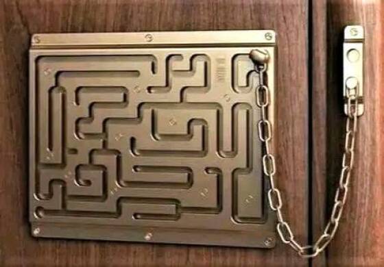 A brass maze puzzle is mounted on a wooden door, with a chain attached to its exit point and leading to a door latch. The…