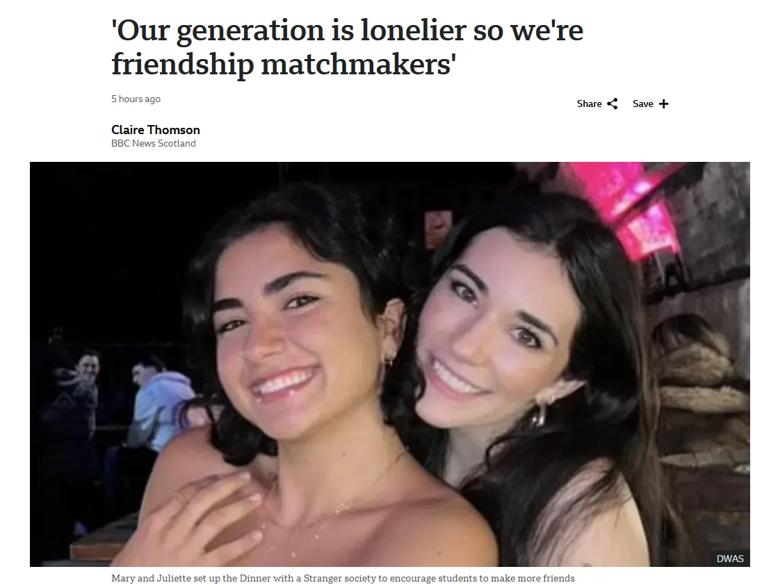 A news article screenshot showing two smiling young women posing closely together in a dimly lit social setting. The…