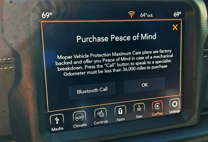 A car's infotainment screen displays a pop-up titled 'Purchase Peace of Mind,' advertising Mopar Vehicle Protection plans…