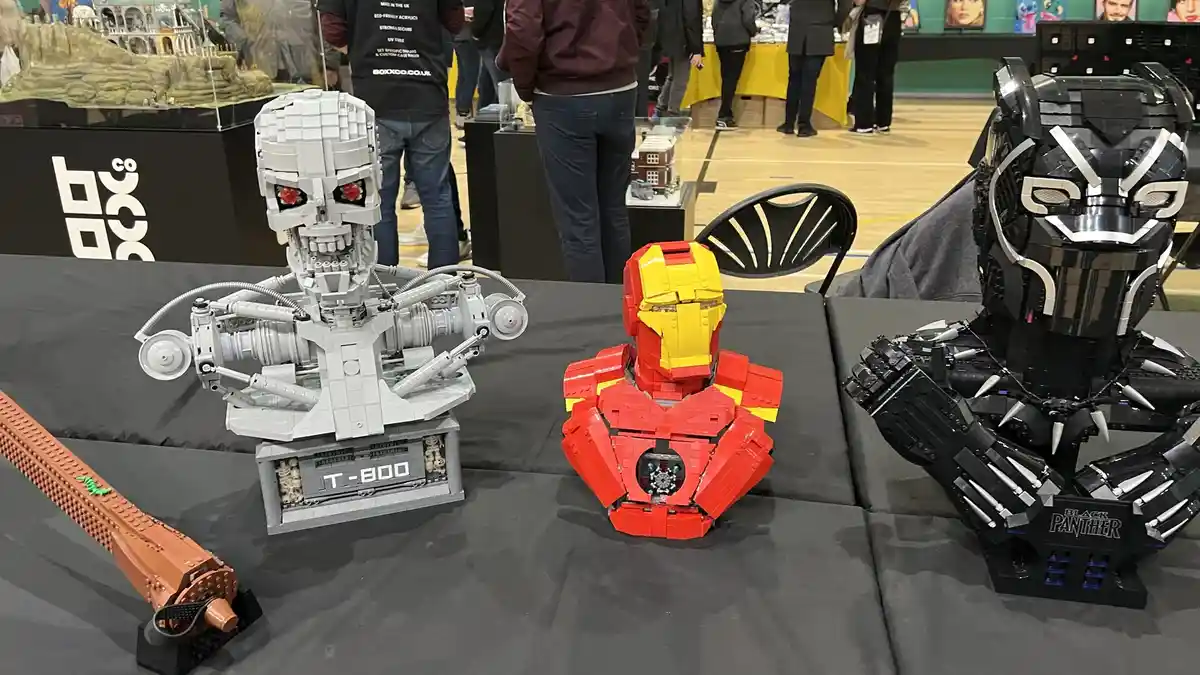 Three detailed LEGO busts of movie characters — a gray T-800 Terminator, a red and gold Iron Man, and a black Black Panther…