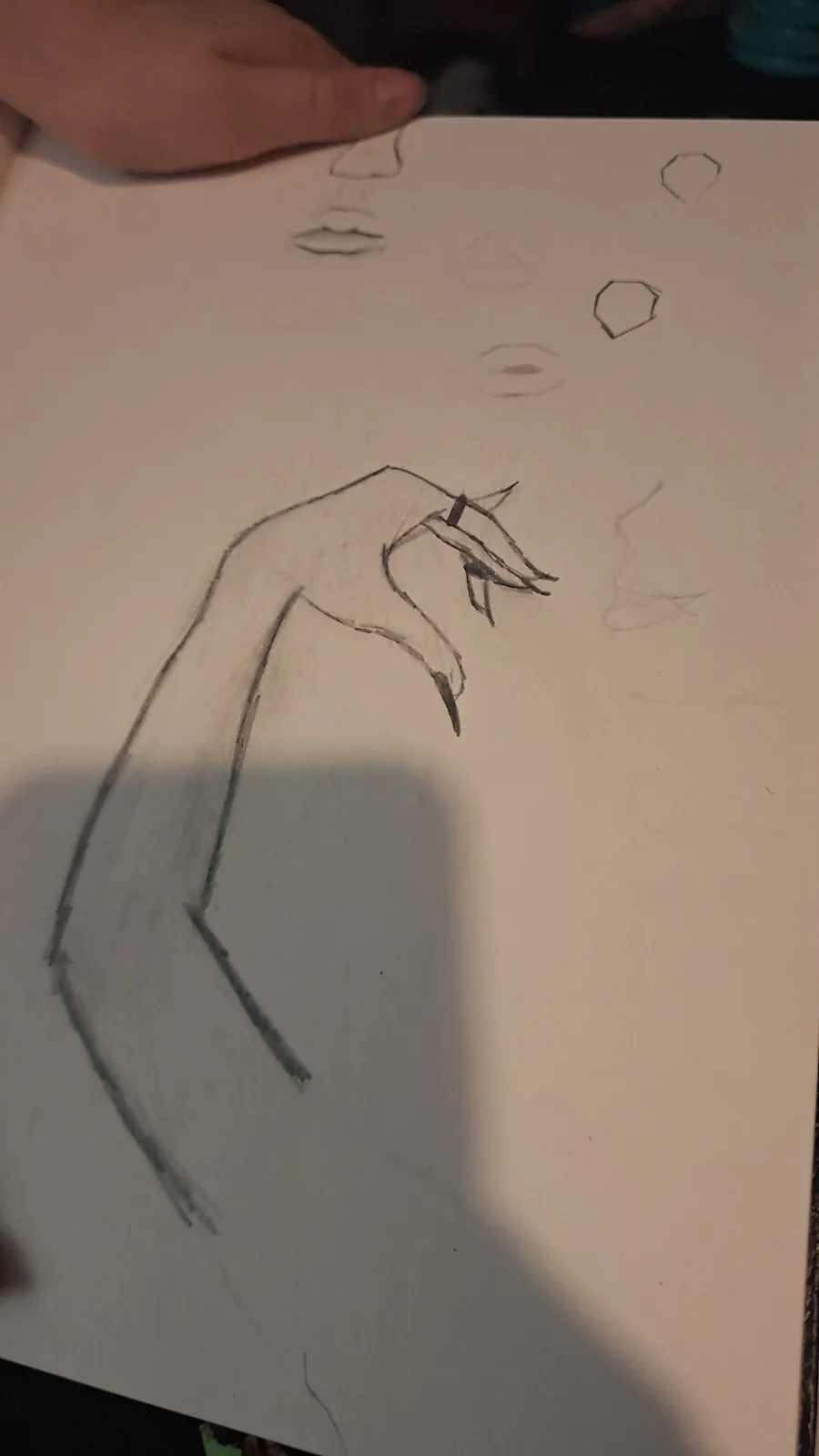 A hand-drawn sketch on paper shows a partially shaded arm ending in a detailed hand with long, sharp claws. Above it, faint…