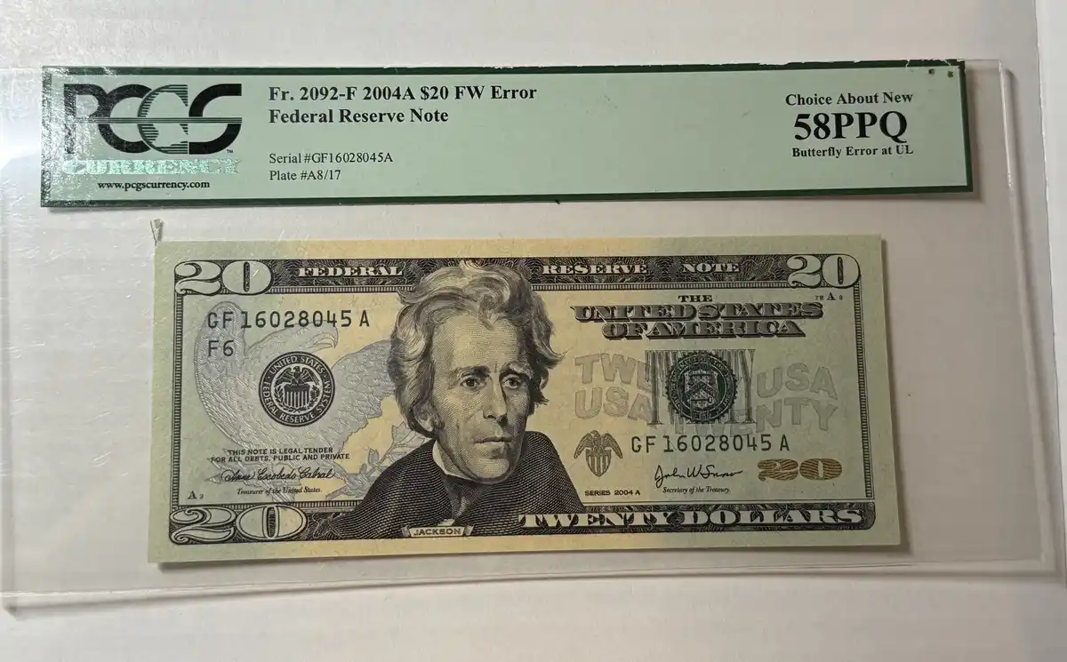 A 2004A U.S. twenty-dollar bill with a 'Butterfly Error at UL' is shown inside a PCGS Currency slab. The label identifies it…
