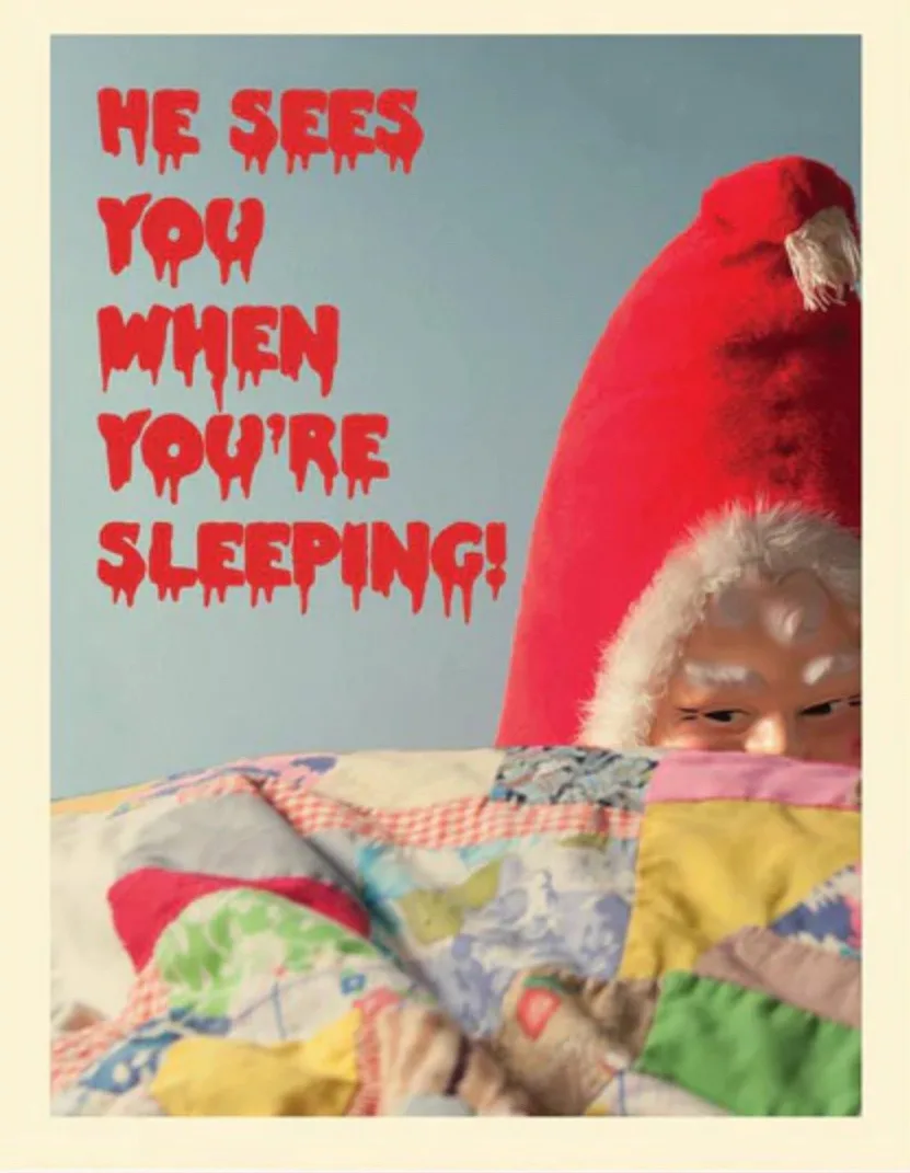 A person wearing a red Santa hat peeks over a colorful patchwork quilt, with the text 'HE SEES YOU WHEN YOU'RE SLEEPING!' in…