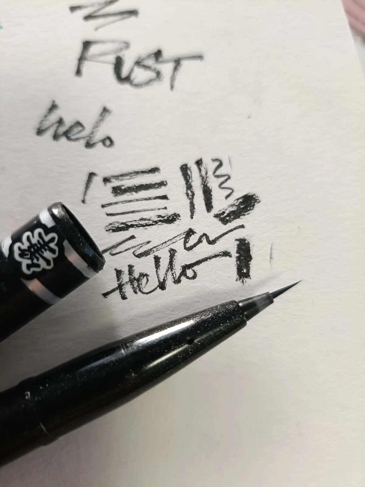A close-up photo shows a black fountain pen with a sharp nib resting on white paper, next to handwritten text. The text…