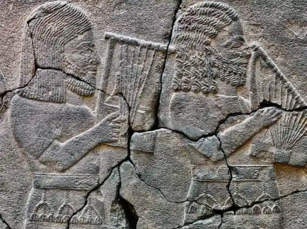 A close-up of an ancient stone relief carving showing two bearded men in traditional attire, each holding and playing a…