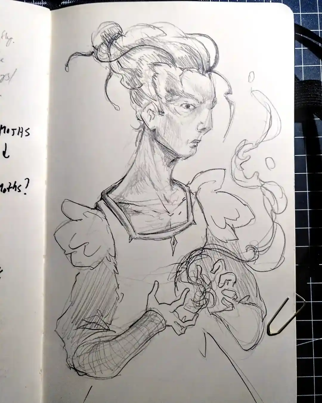 A pencil sketch in a sketchbook shows a person with messy hair and a stern expression, wearing a detailed outfit with puffy…