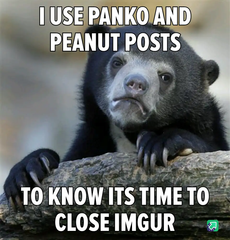 A close-up photo of a sad-looking, dark-furred bear with a downturned mouth, resting its paws on a log. The bear has a…