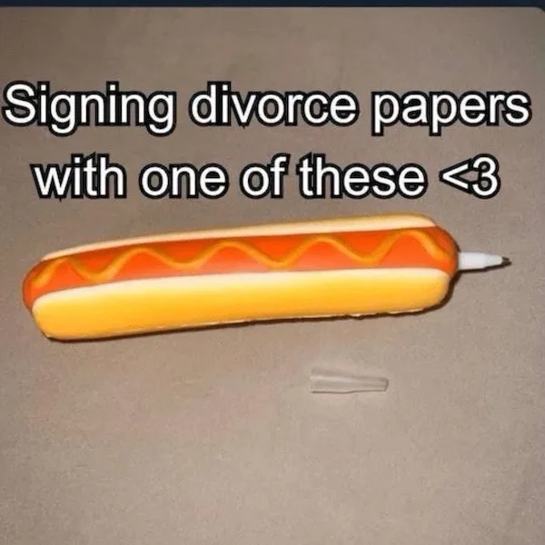 A close-up photo shows a novelty pen shaped like a hot dog with mustard, lying on a beige surface with its cap removed…