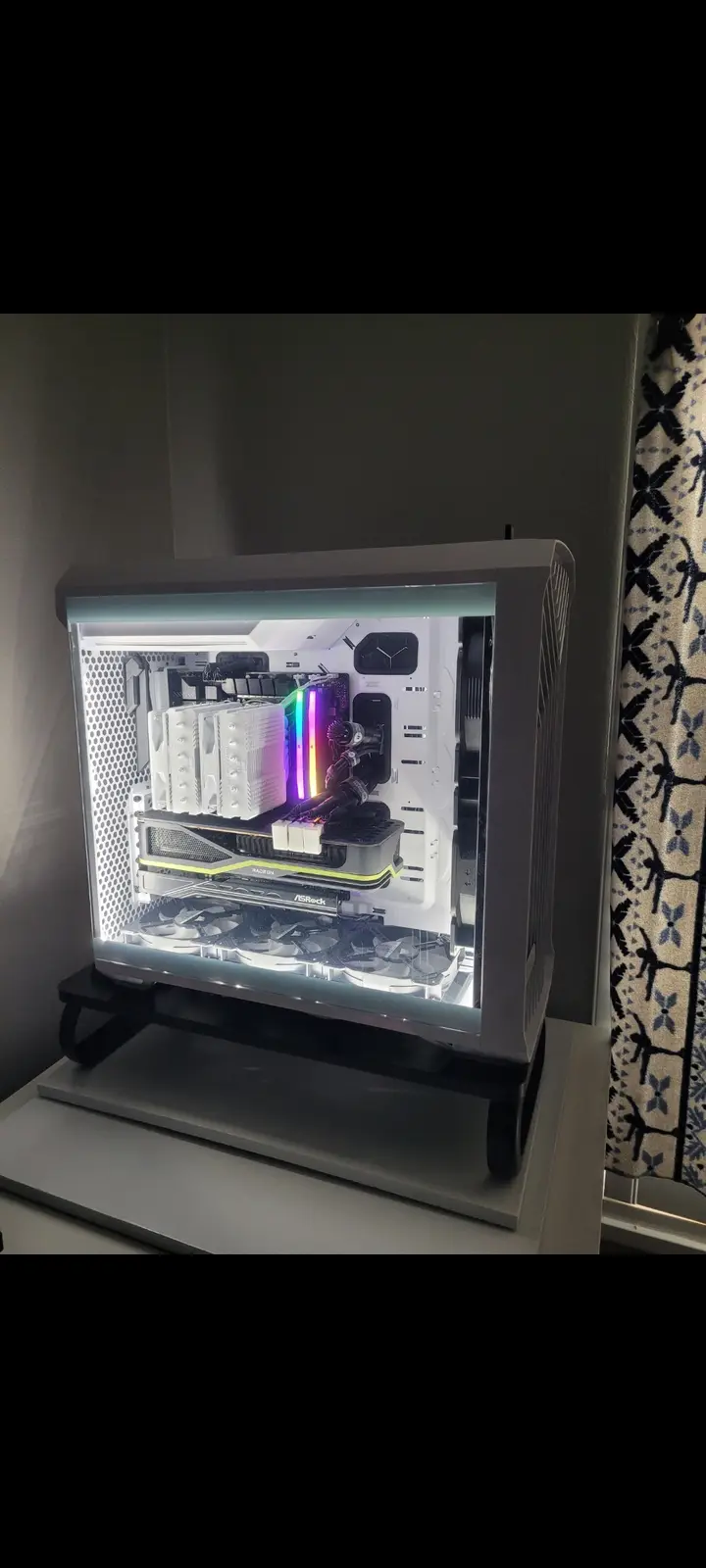 A white computer case with a transparent side panel is shown, revealing its internal components illuminated by RGB lighting…